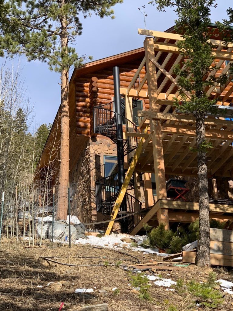 A log cabin is being built in the woods with a spiral staircase.