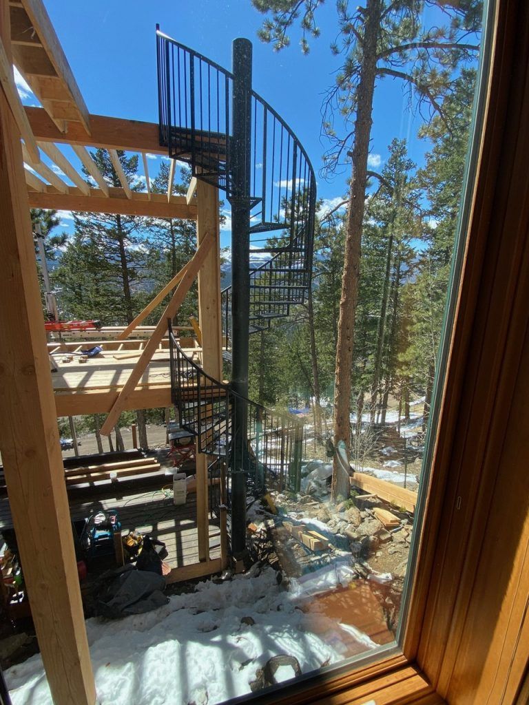 A spiral staircase is visible through a window in a house under construction.