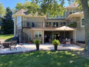 A large house with a spiral staircase and a patio with chairs and umbrellas.