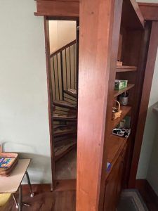 A spiral staircase is behind a wooden door in a room.