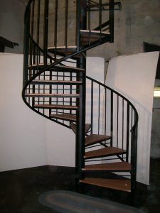 A spiral staircase with wooden steps and a black railing