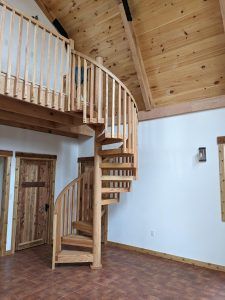 A wooden spiral staircase in a room with a wooden railing.