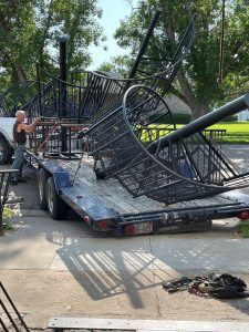 A man is standing next to a trailer with a large metal object on it.