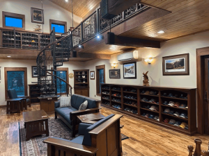 A living room with a couch , chairs , shelves and a spiral staircase.