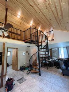 A living room with a spiral staircase and a ceiling fan.