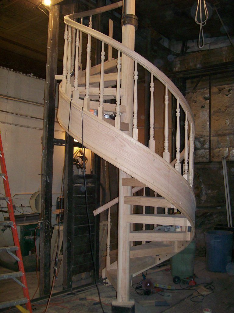 A wooden spiral staircase is being built in a building