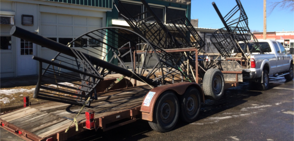 A trailer with stairs on it is parked in front of a building.