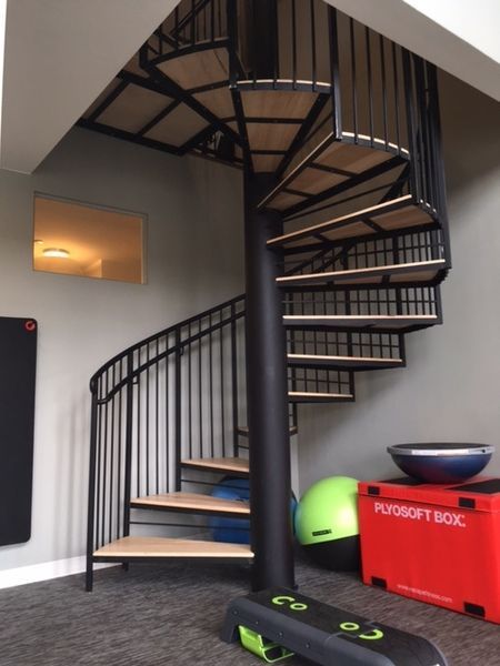 A spiral staircase in a gym next to a red box that says putosoft box