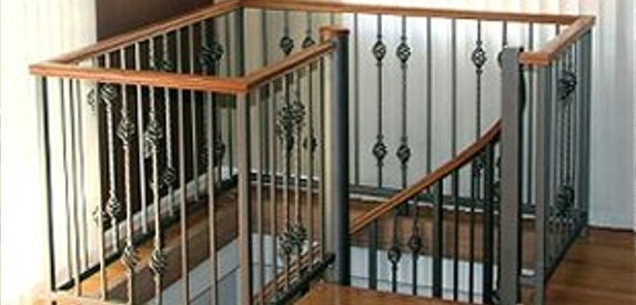 A staircase with a wrought iron railing and wooden handrails.