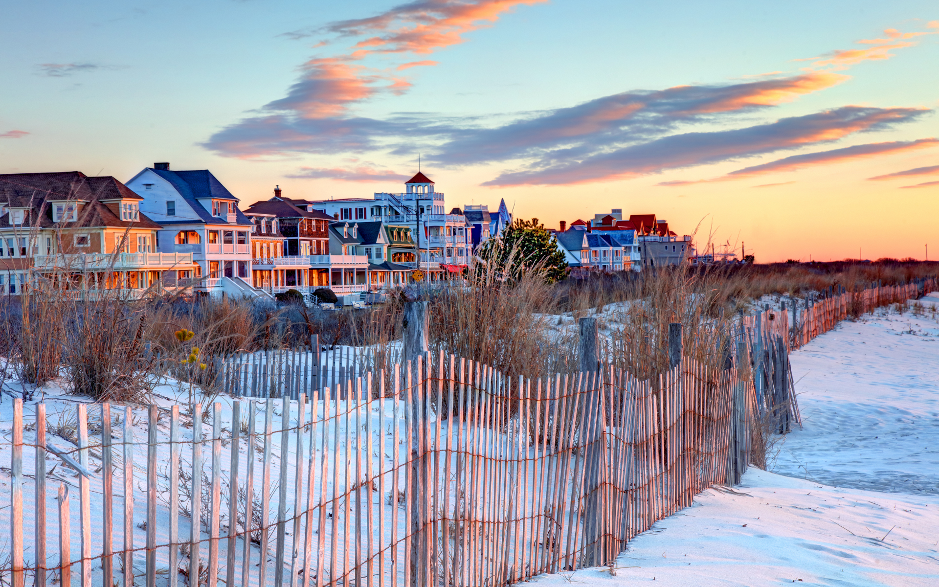 A row of houses on a New Jersey beach with a wooden fence in the foreground.