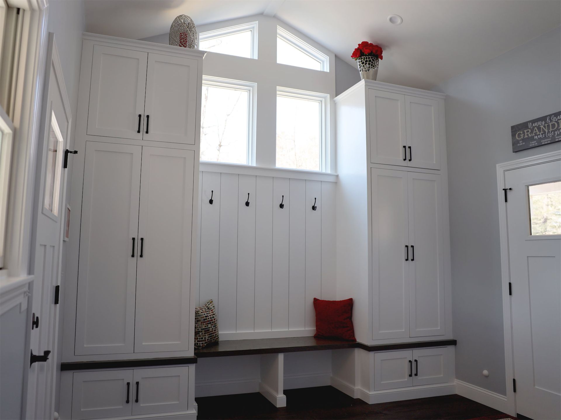 a room with lots of white cabinets and a bench