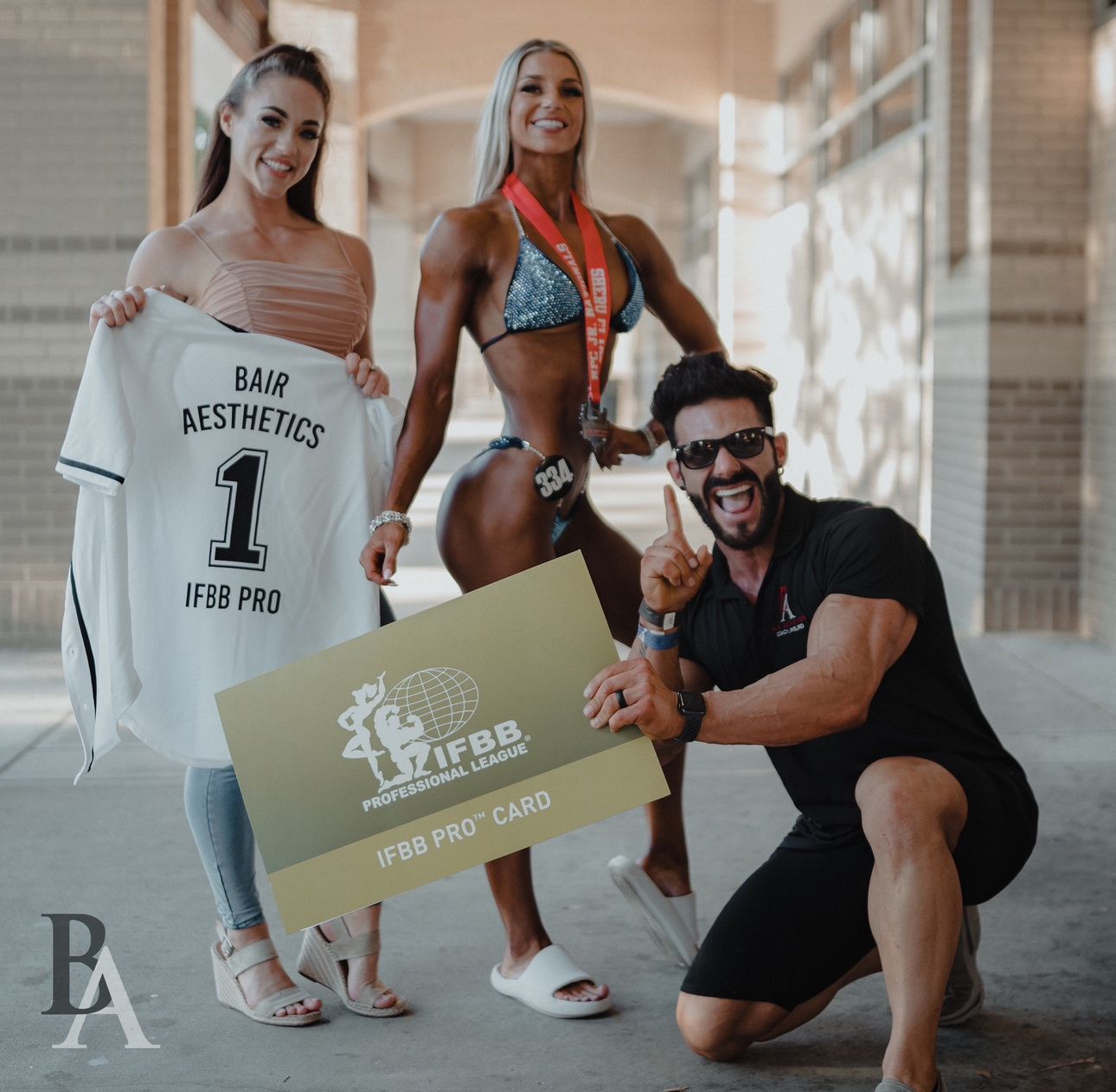 A man and two women are posing for a picture while holding a card and a shirt.
