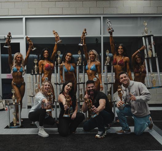 A group of people posing for a picture holding trophies