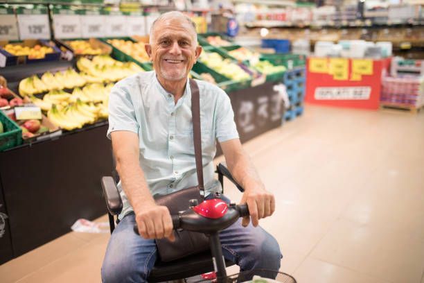 Portrait of a senior man with a disability shopping in the supermarket using his power wheelchair.