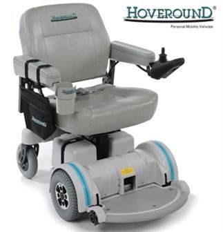 Gray Hoveround power wheelchair with joystick, armrests, cup holder, and black side bag.