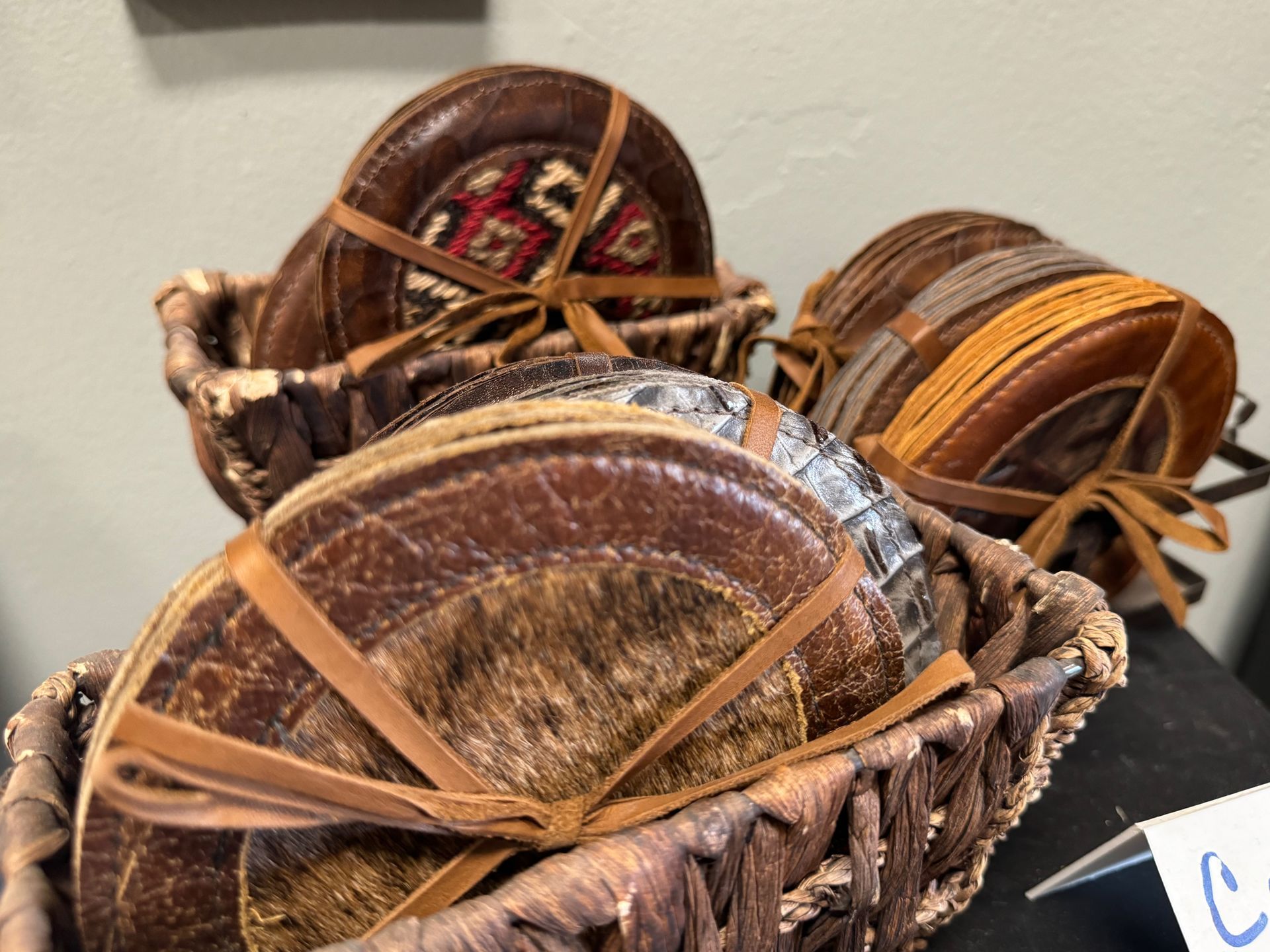 A wicker basket filled with a variety of leather coasters