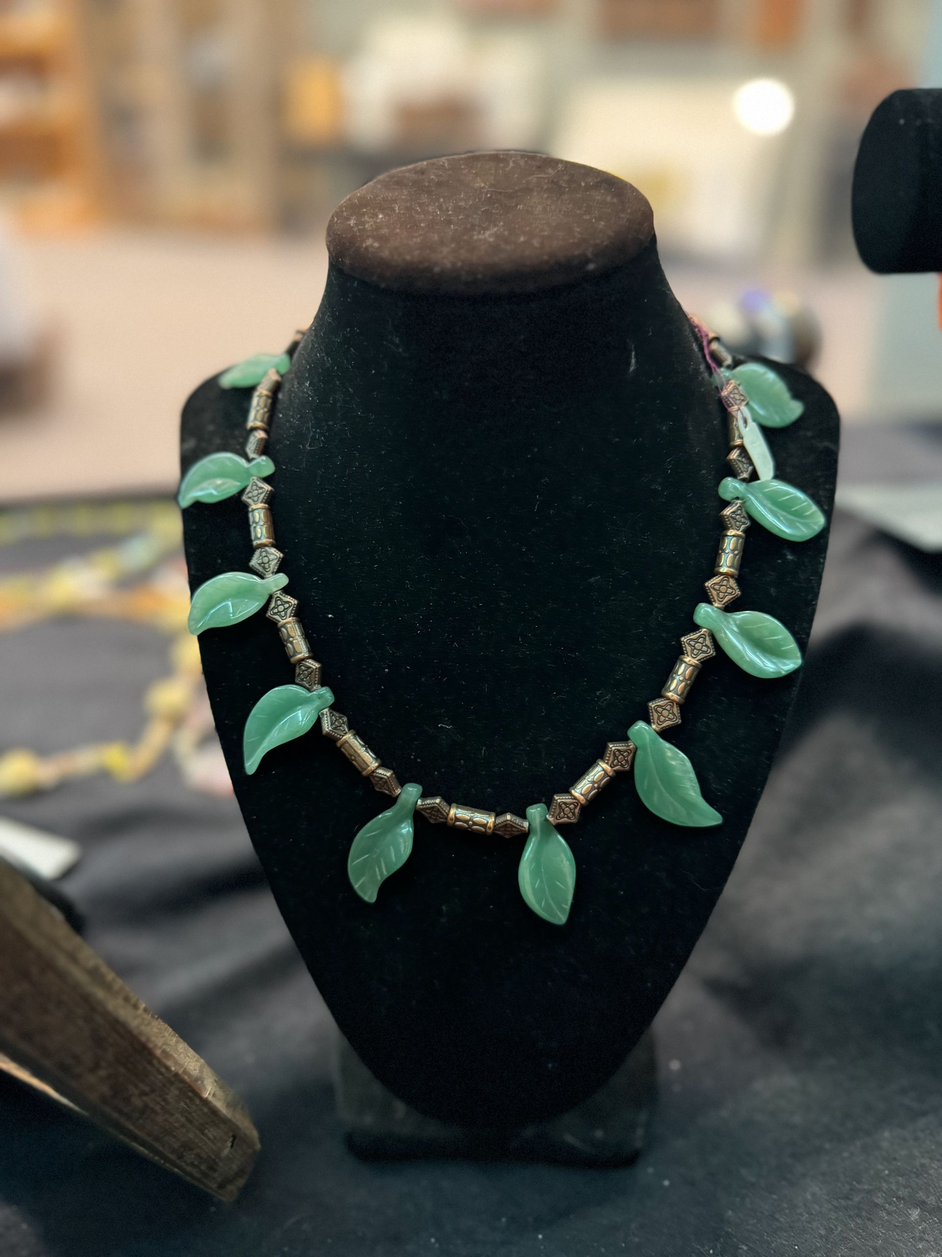 A necklace with green beads is on a mannequin