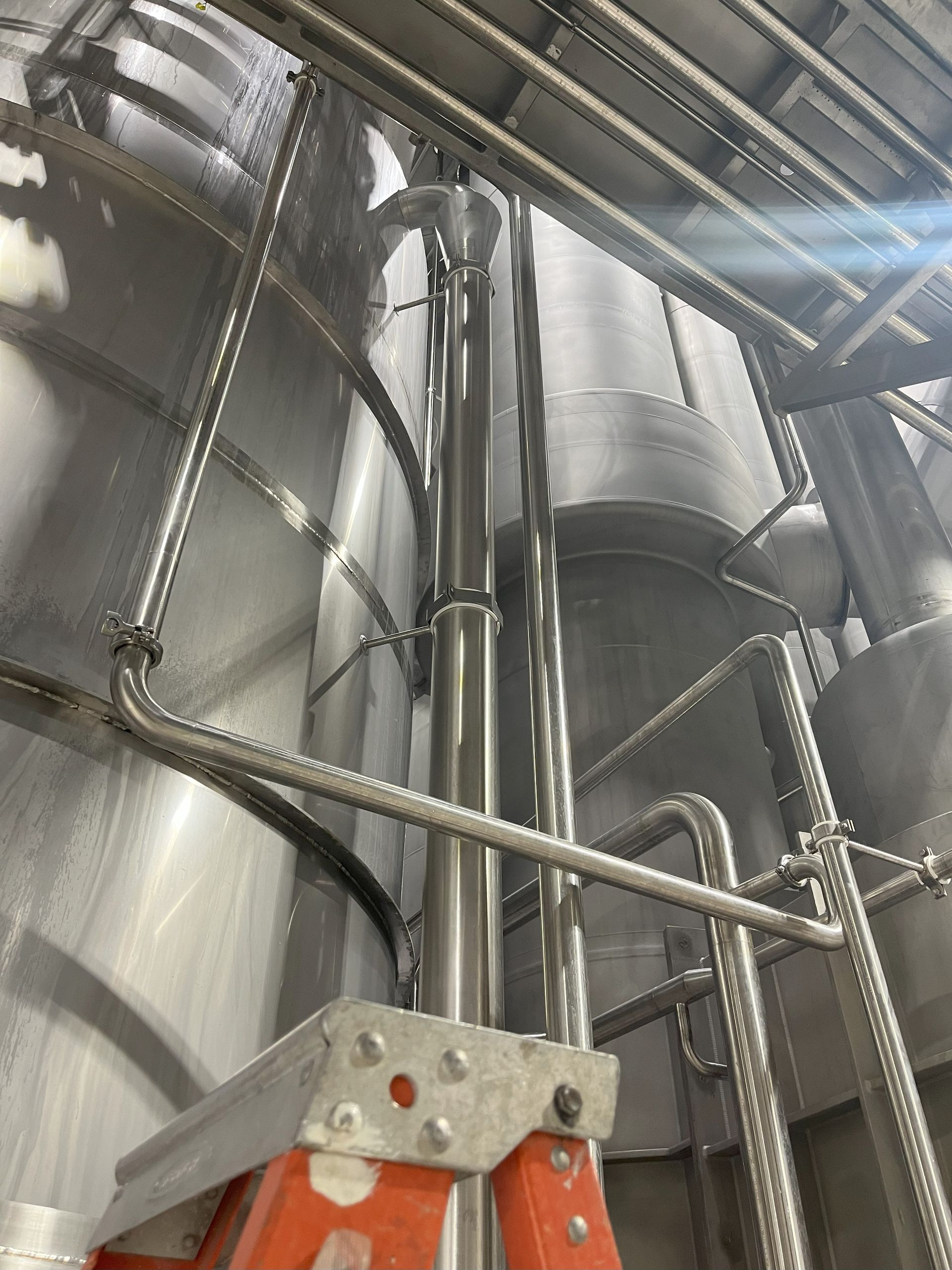 A ladder is sitting on top of a metal pipe in a factory.