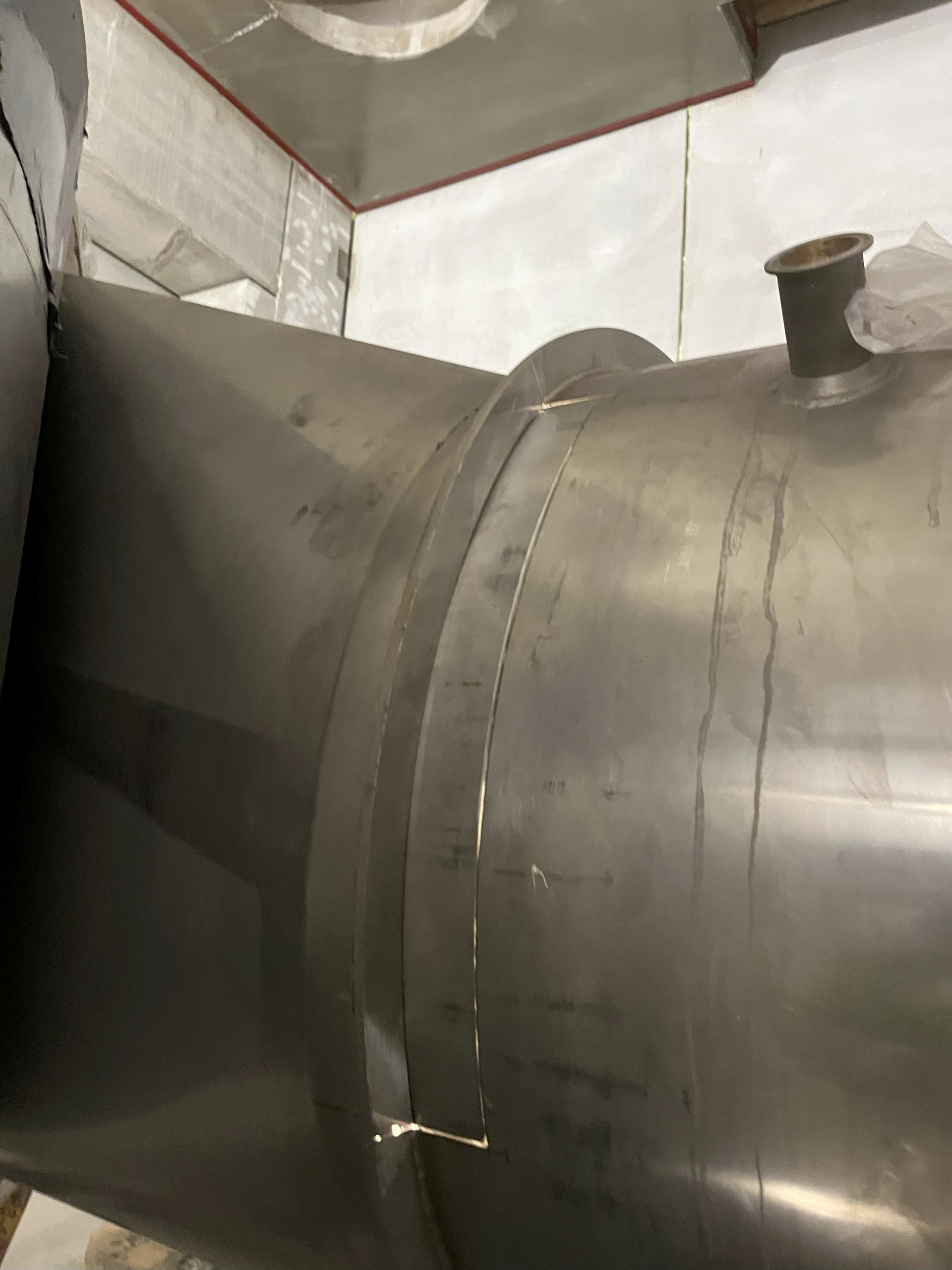 A large stainless steel pipe is sitting in a room.