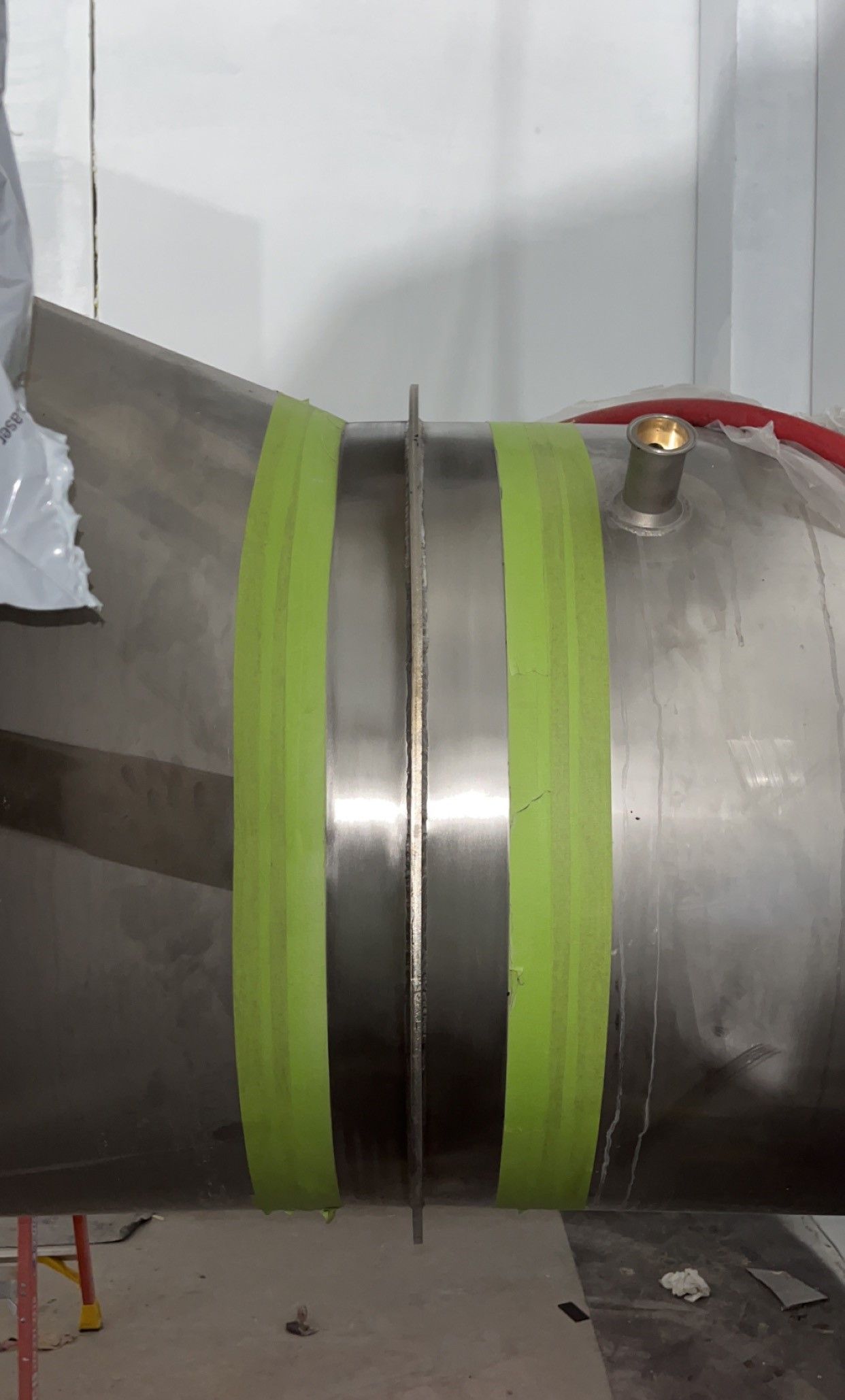 A stainless steel pipe with green tape on it.