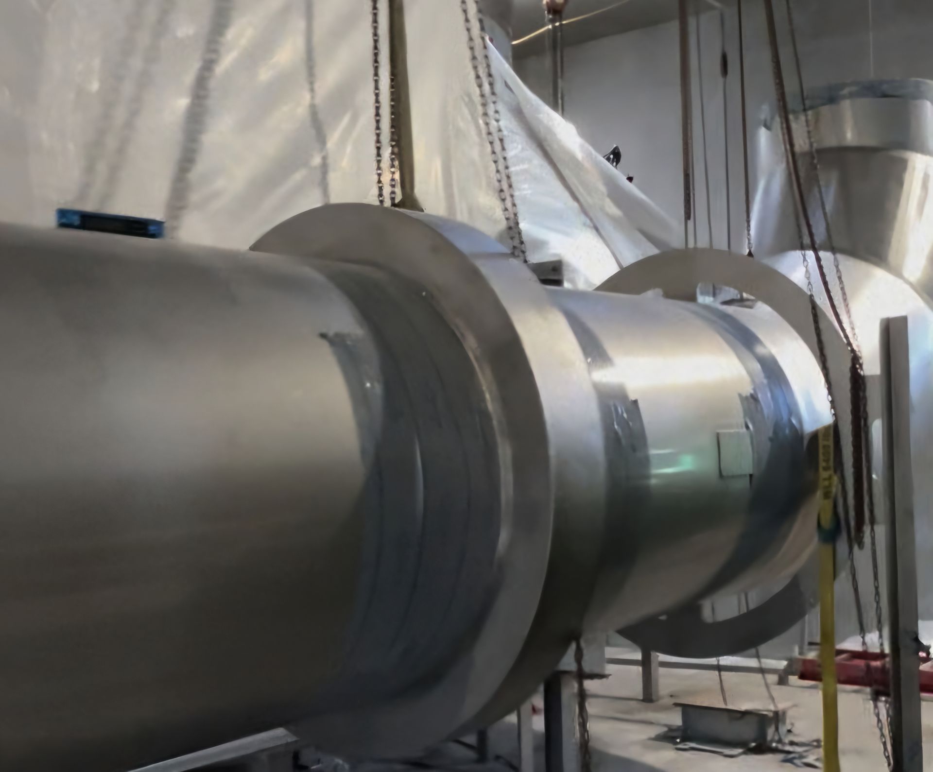 A row of stainless steel pipes are hanging from the ceiling in a room.