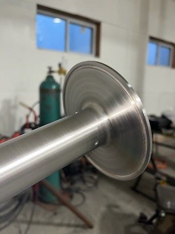 A close up of a stainless steel pipe in a garage.