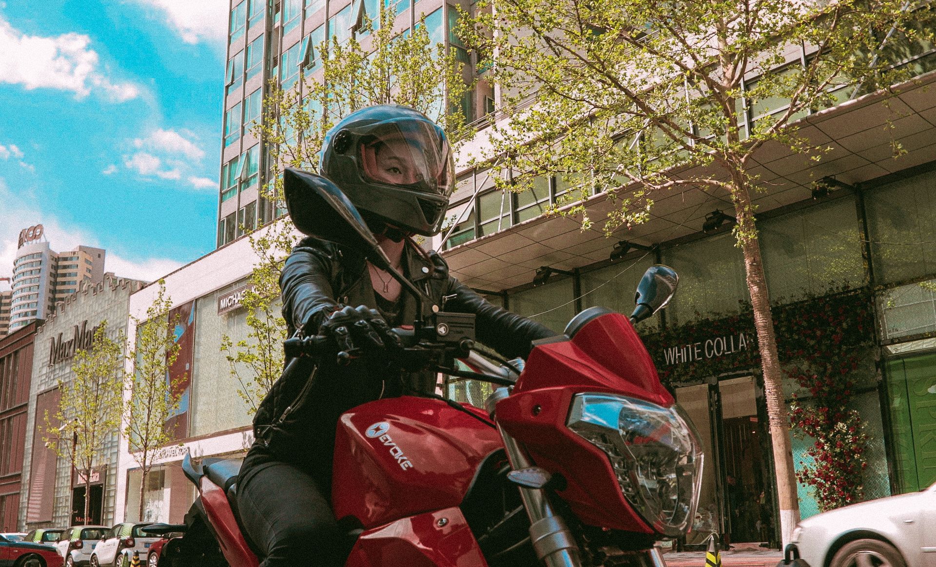 A woman is riding a red electric motorcycle down a city street. 2019 Urban S NYC, USA