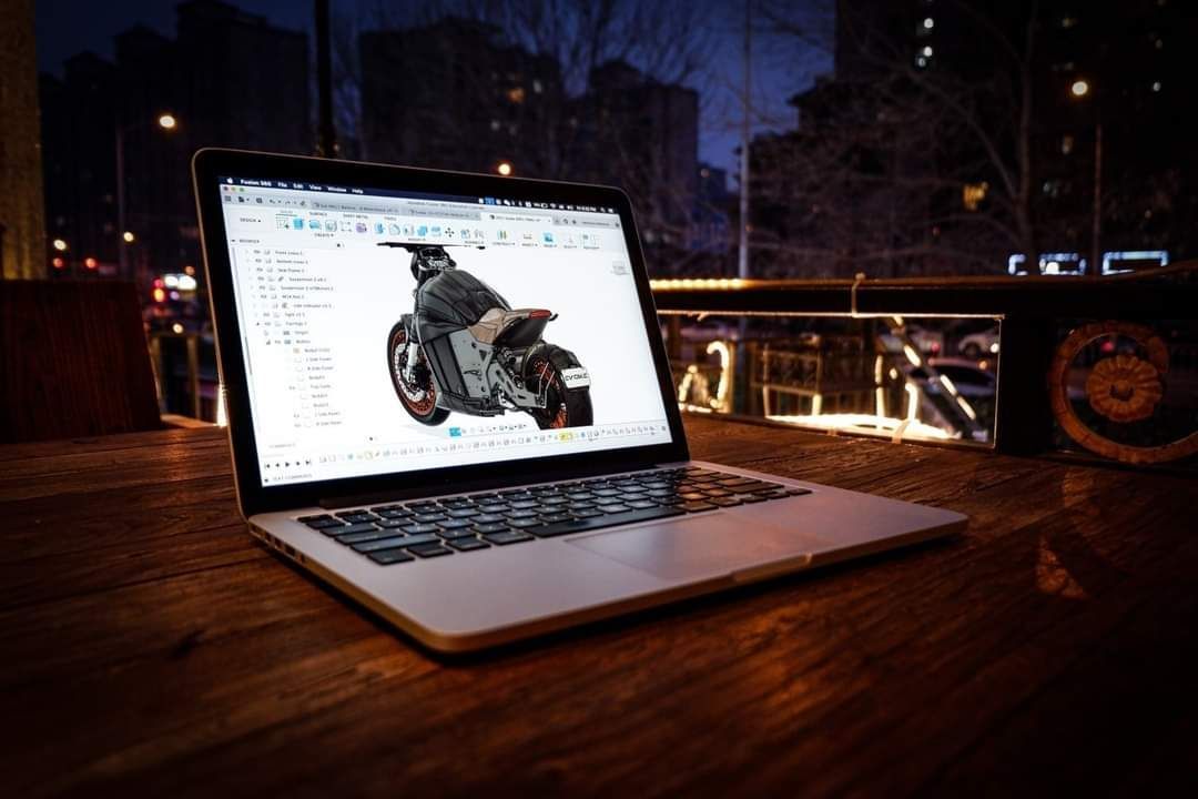 A laptop computer is sitting on a wooden table with a picture of 6061-GT an electric motorcycle on the screen.