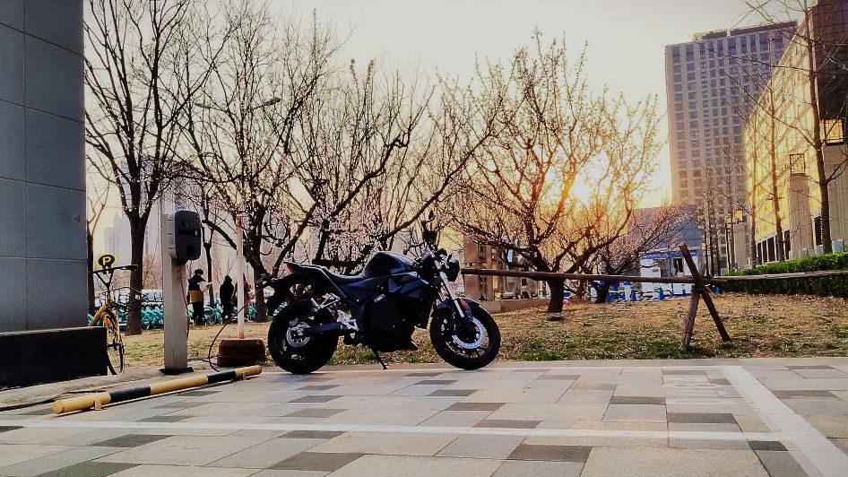 An electric motorcycle is parked in a parking lot in front of a building. Urban Classic 2019 Beijing, China