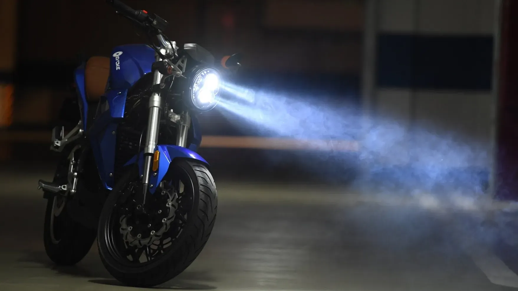 A blue Urban Classic electric motorcycle is parked in a parking garage at night.