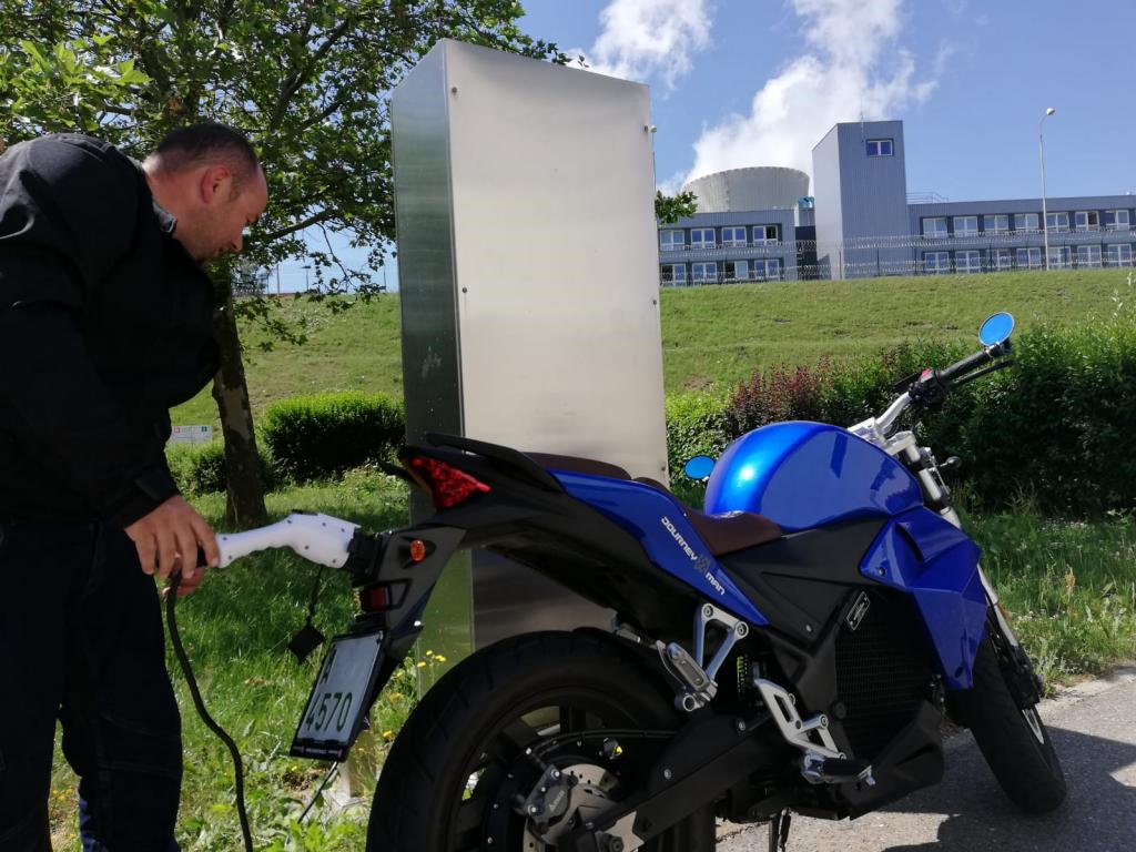A man is plugging an electric motorcycle into a charging station
