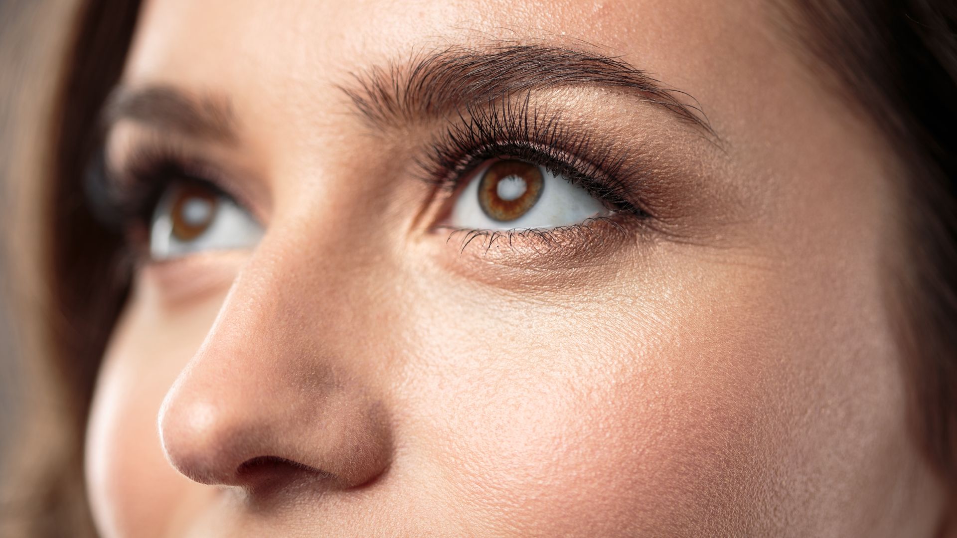 A close up of a woman 's face with her eyes looking up.