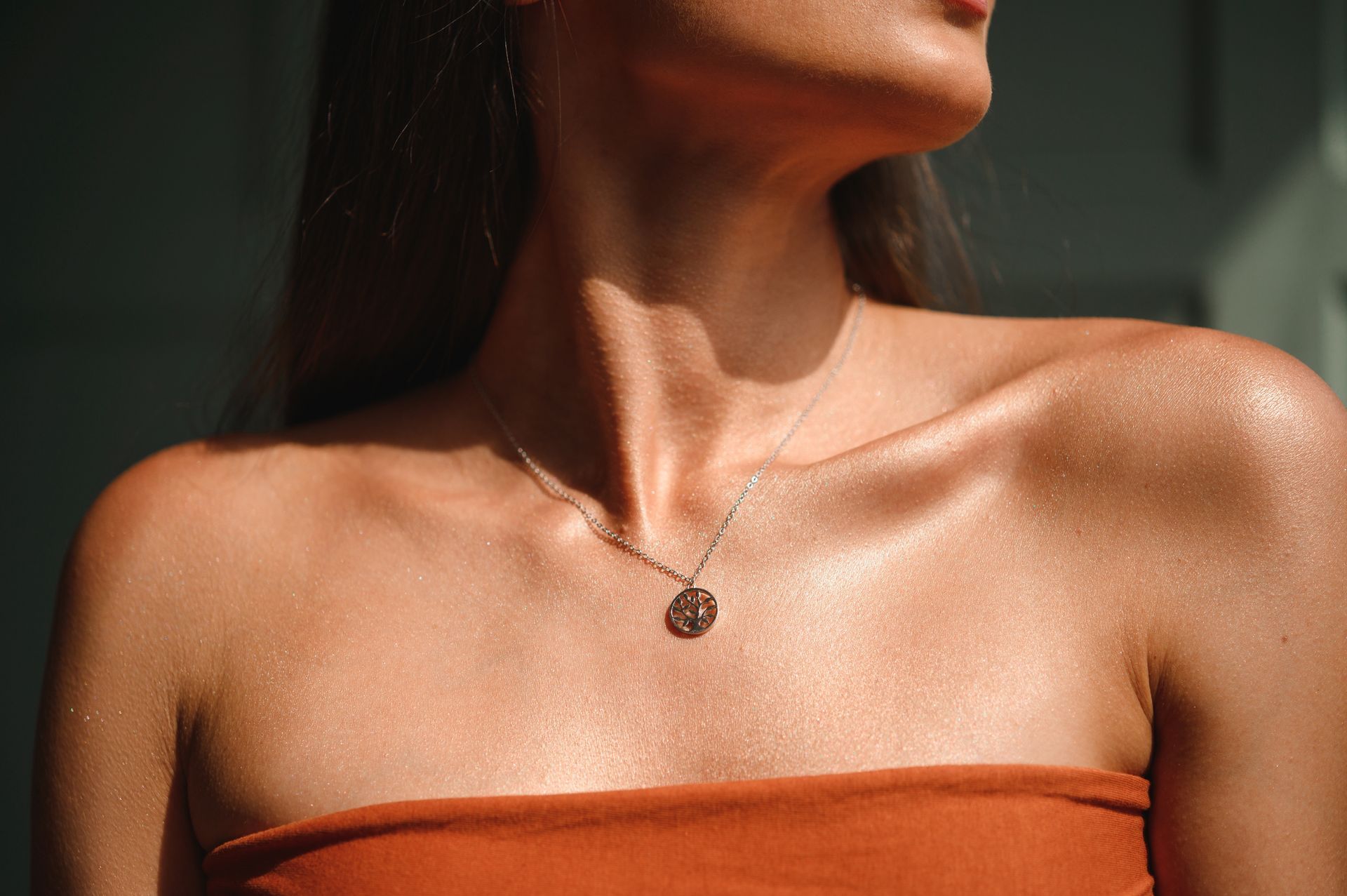 a woman wearing a necklace with a coin on it