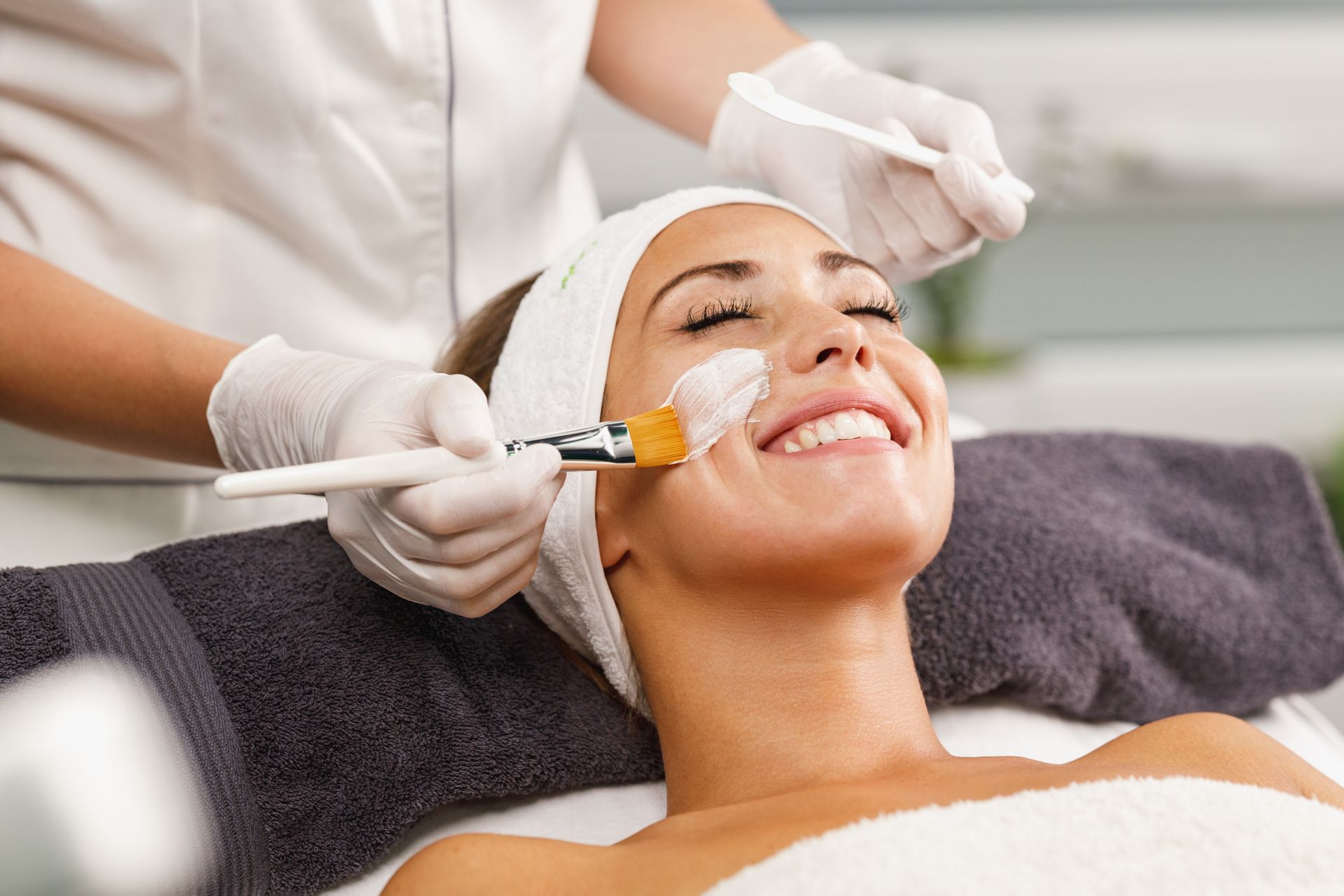 a woman is smiling while getting a facial treatment