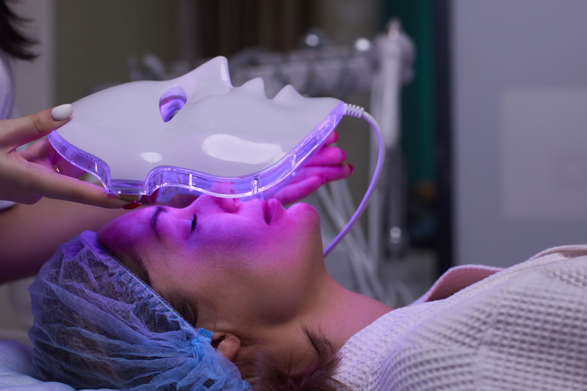 a woman is getting a purple light treatment on her face