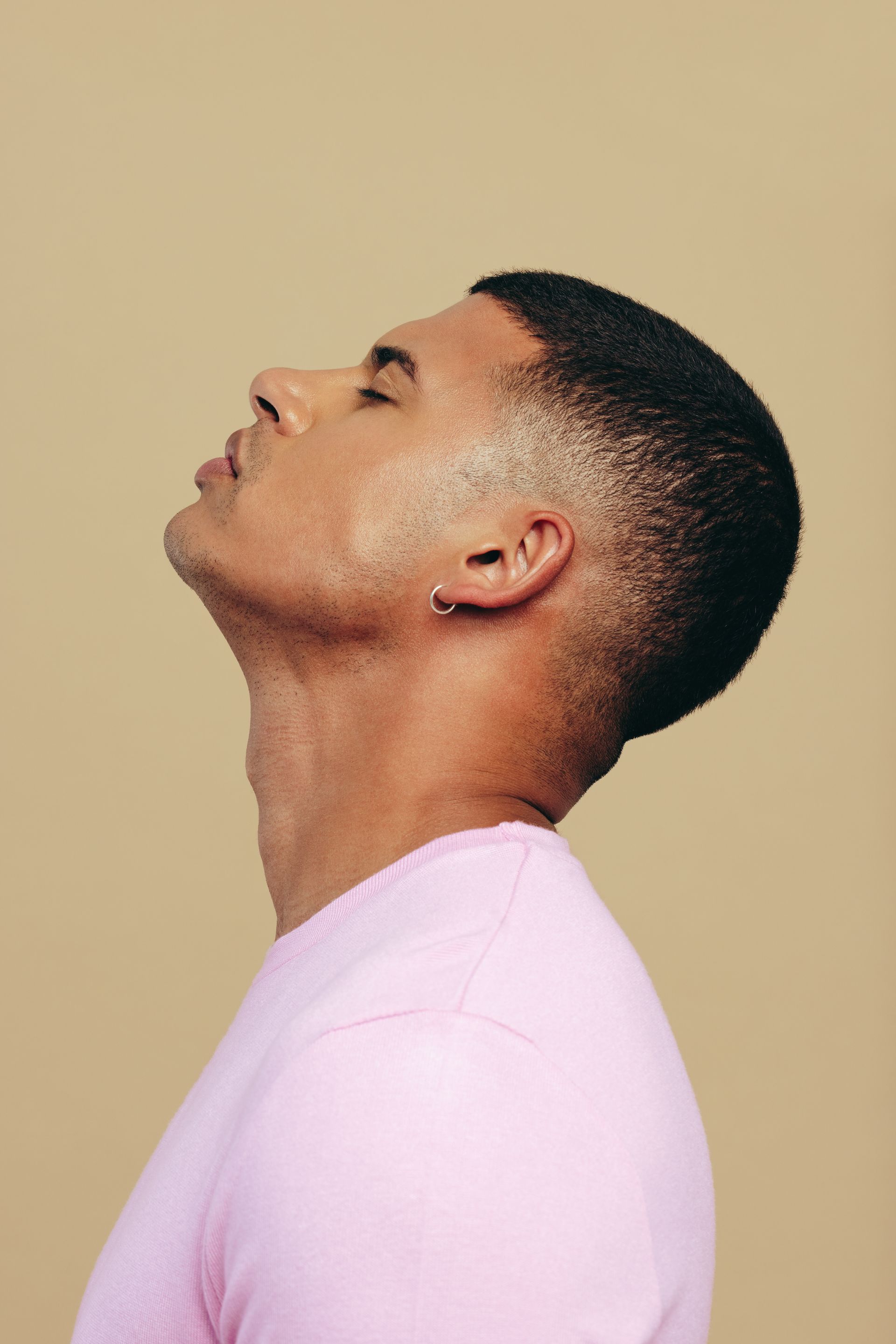 a man in a pink shirt has a piercing in his ear