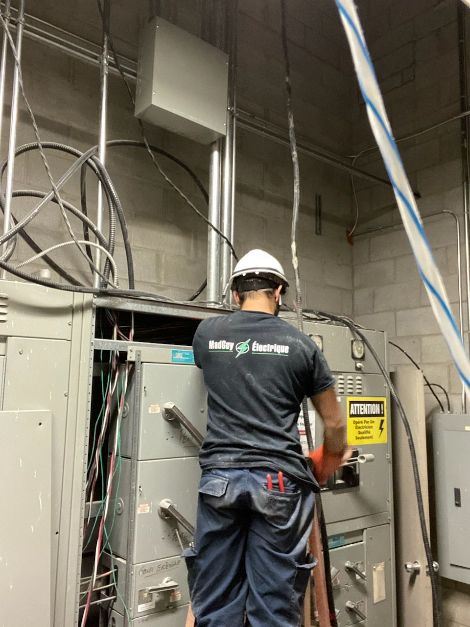 Un homme en chemise noire travaille sur un boîtier électrique