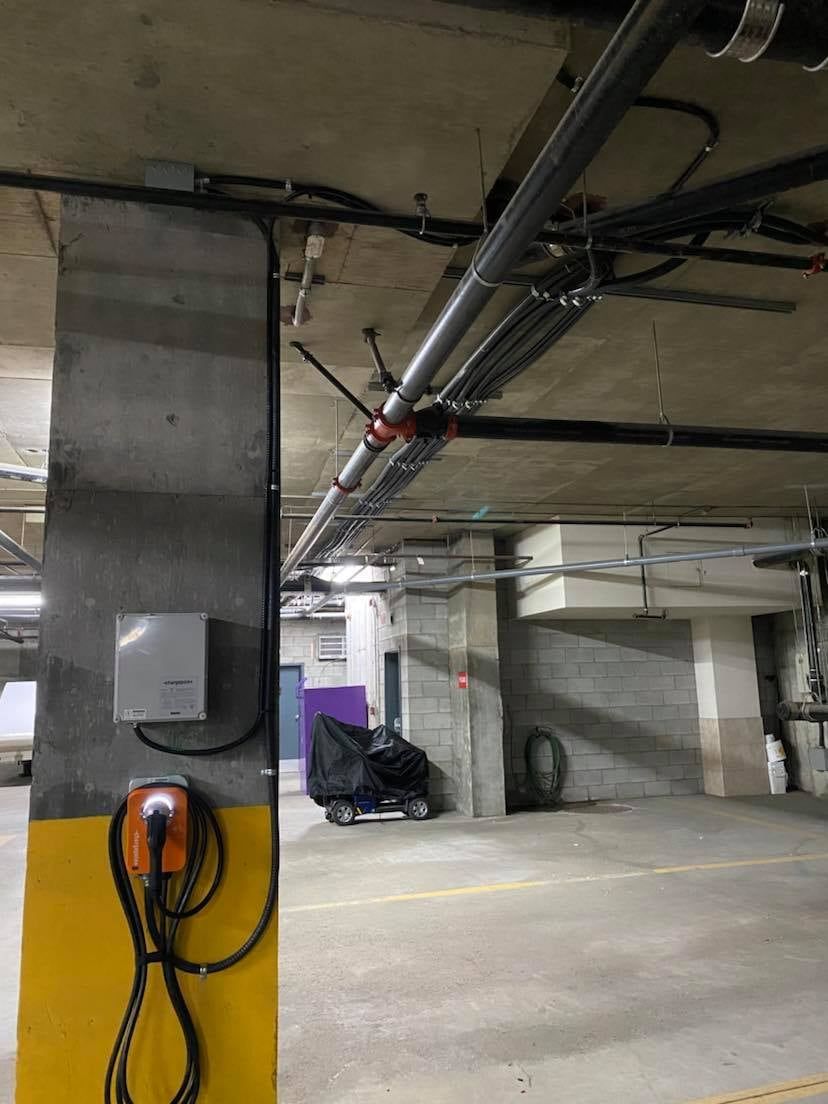 Une moto est garée dans un parking à côté d'une borne de recharge.