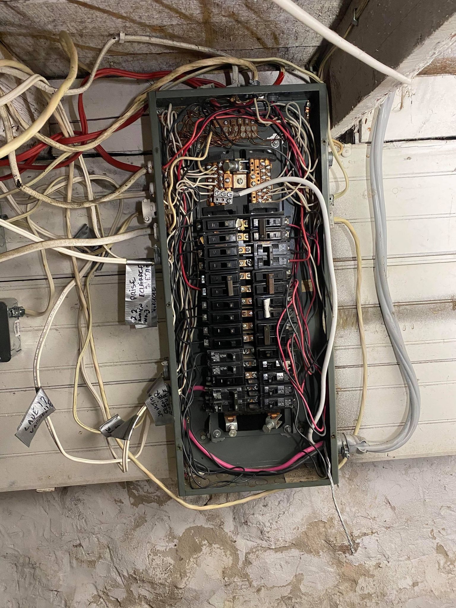 Un panneau électrique très en désordre avec beaucoup de fils qui en sortent.