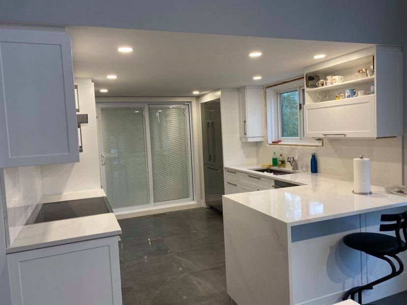 Une cuisine avec des armoires blanches et des portes coulissantes en verre.