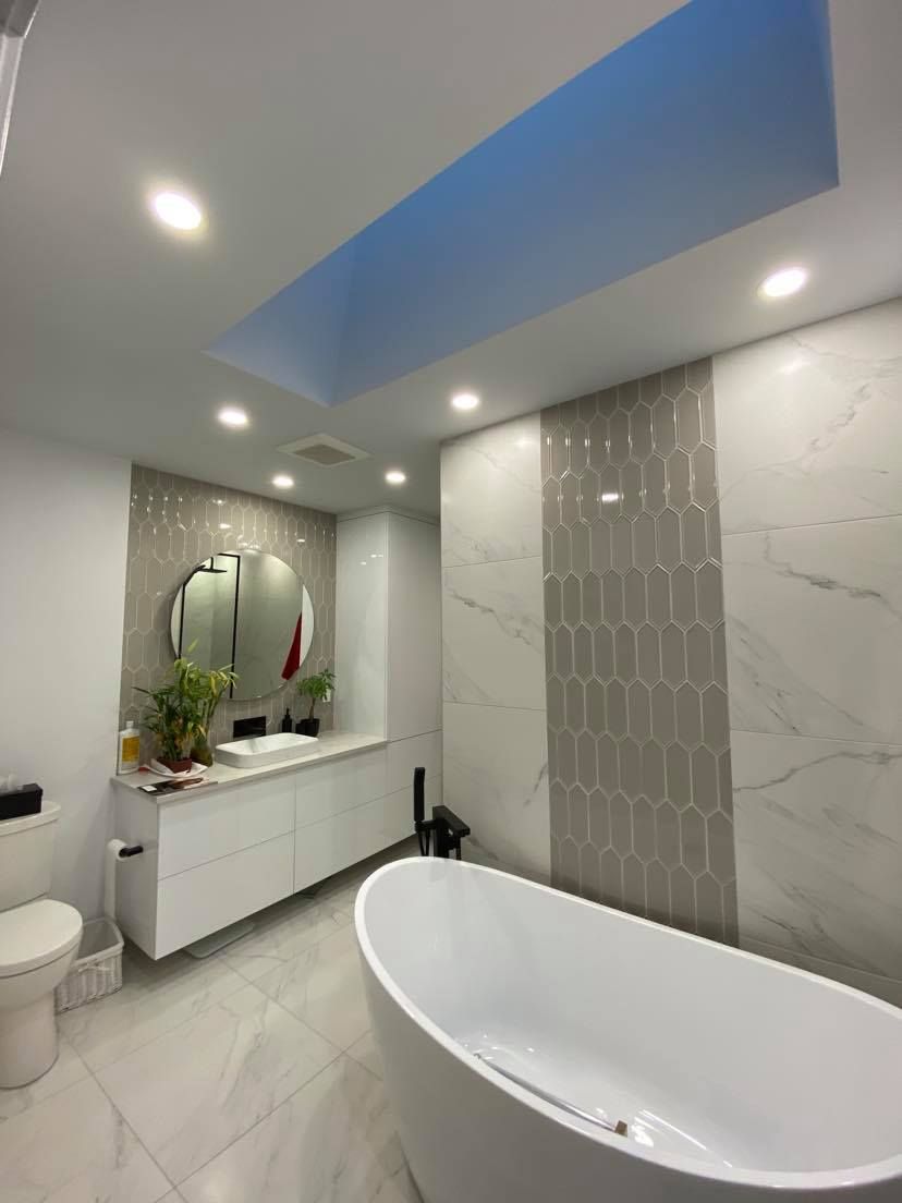 Une salle de bain avec baignoire, lavabo, miroir et WC.