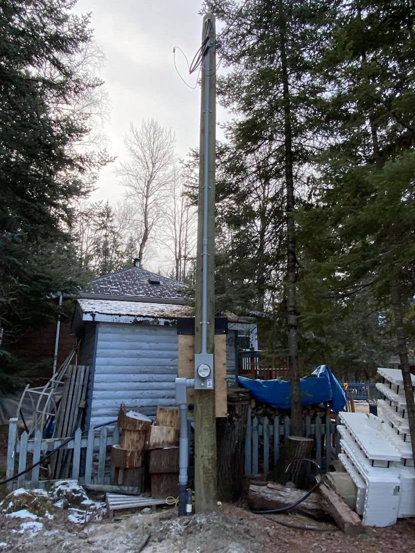 Un poteau téléphonique se trouve devant une maison dans les bois.
