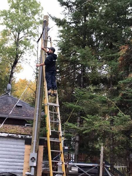 Un homme est debout sur une échelle et travaille sur un poteau.