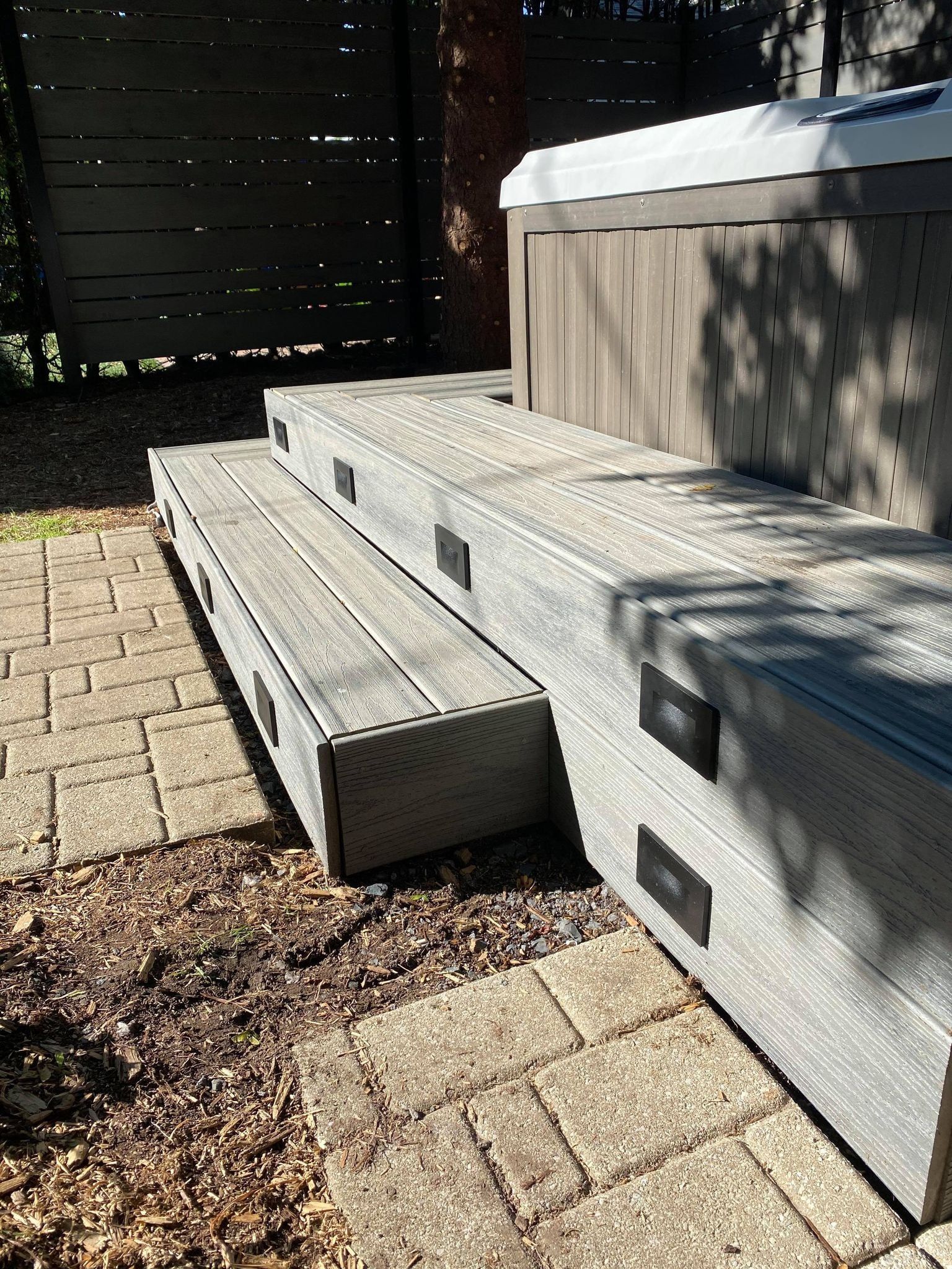 Un bain à remous est posé sur une terrasse en bois avec des marches qui y mènent.