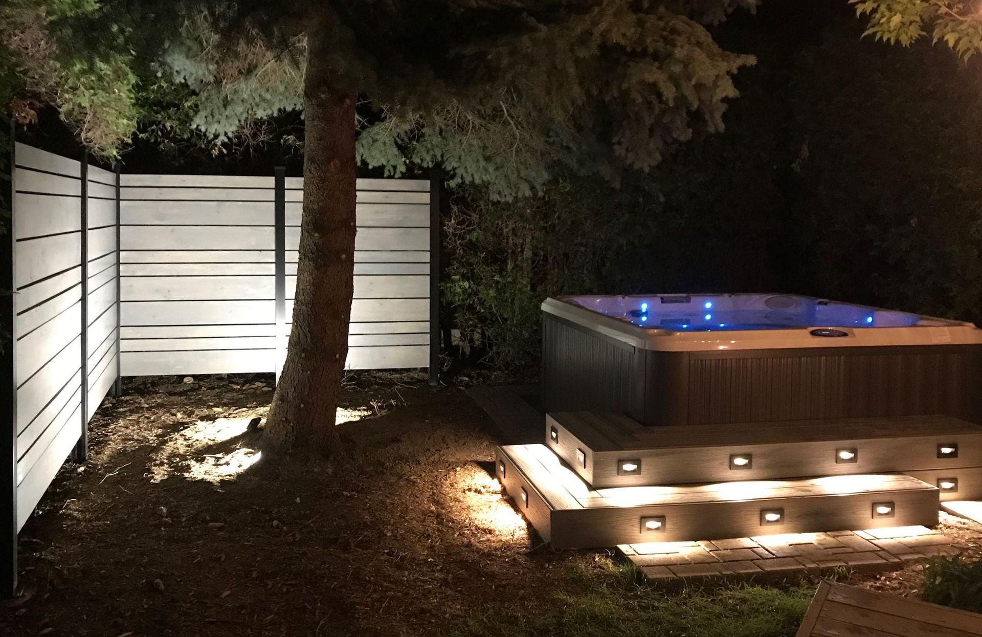Un jacuzzi est éclairé la nuit dans une cour arrière