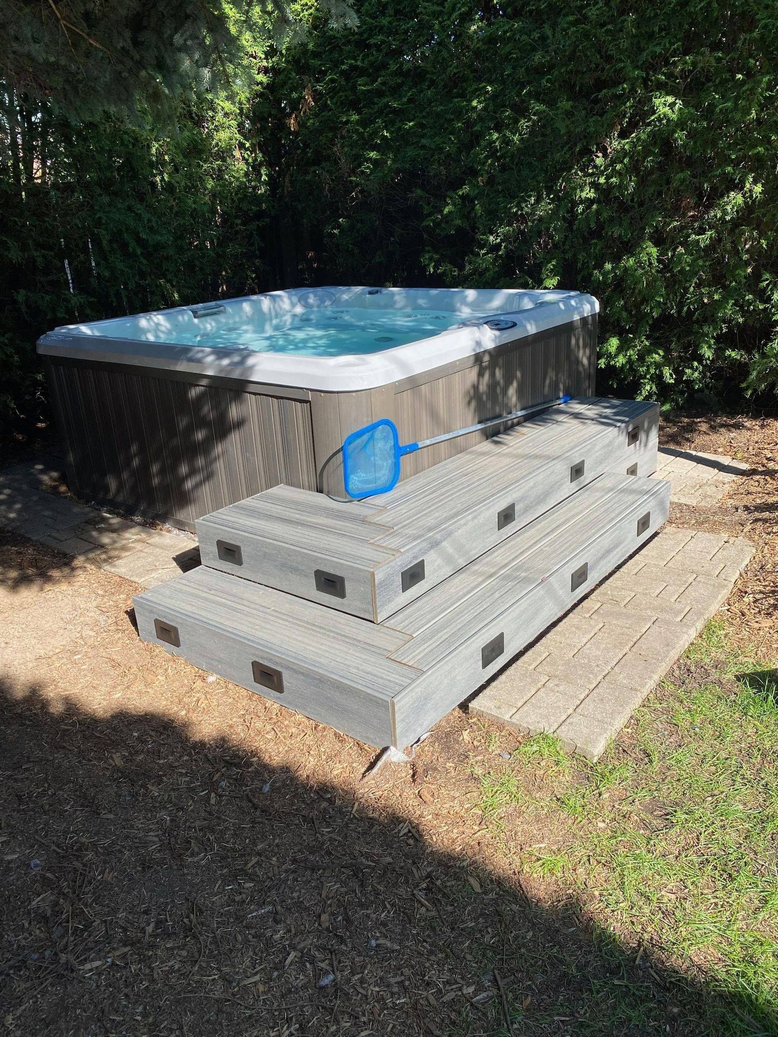 Un bain à remous est posé sur une terrasse en bois dans une cour arrière.