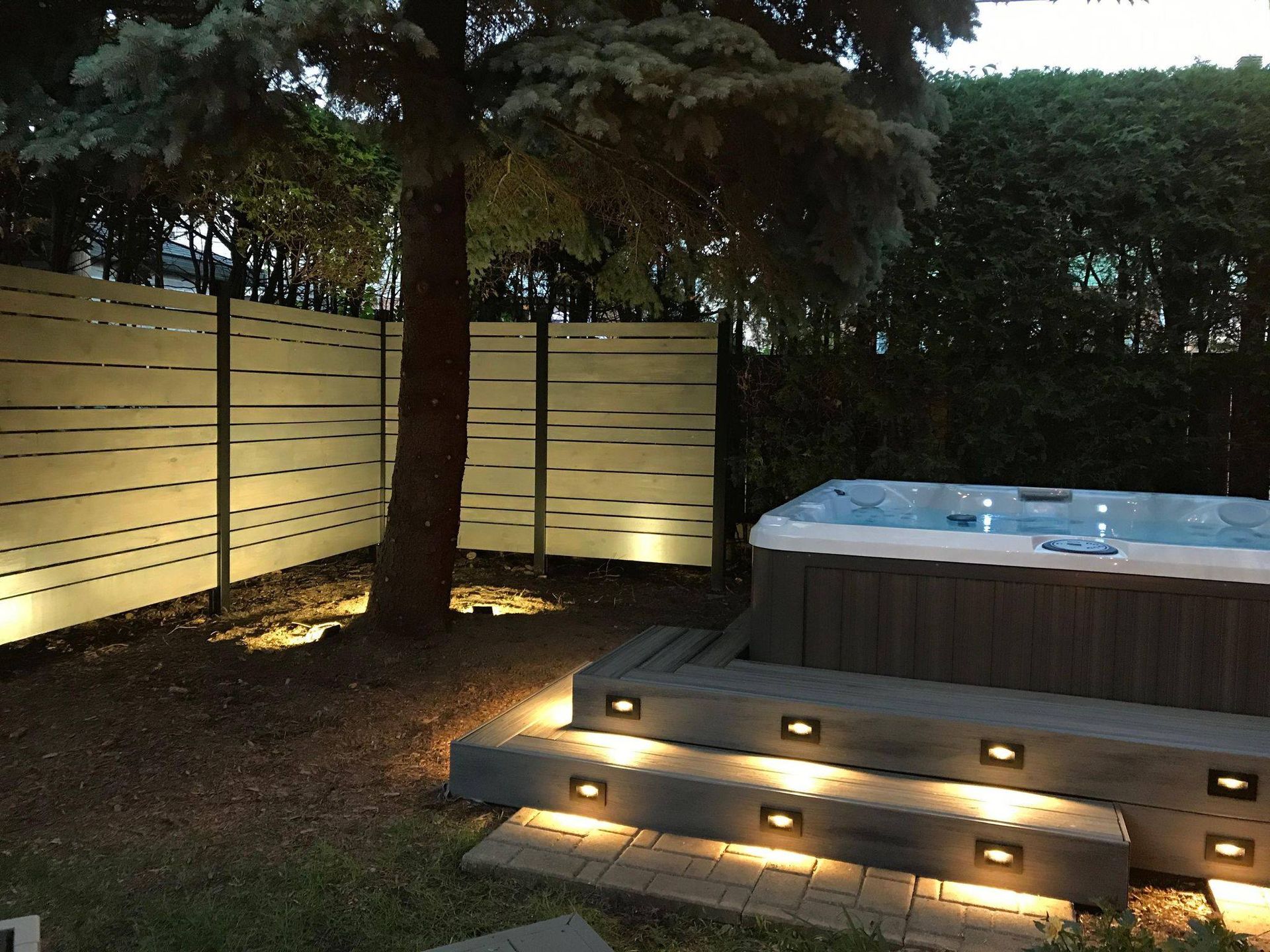 Un jacuzzi dans une cour arrière avec des lumières sur les marches