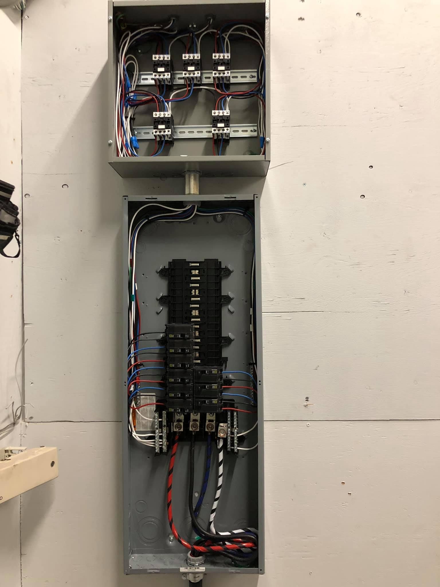 Une boîte électrique avec beaucoup de fils accrochés à un mur.