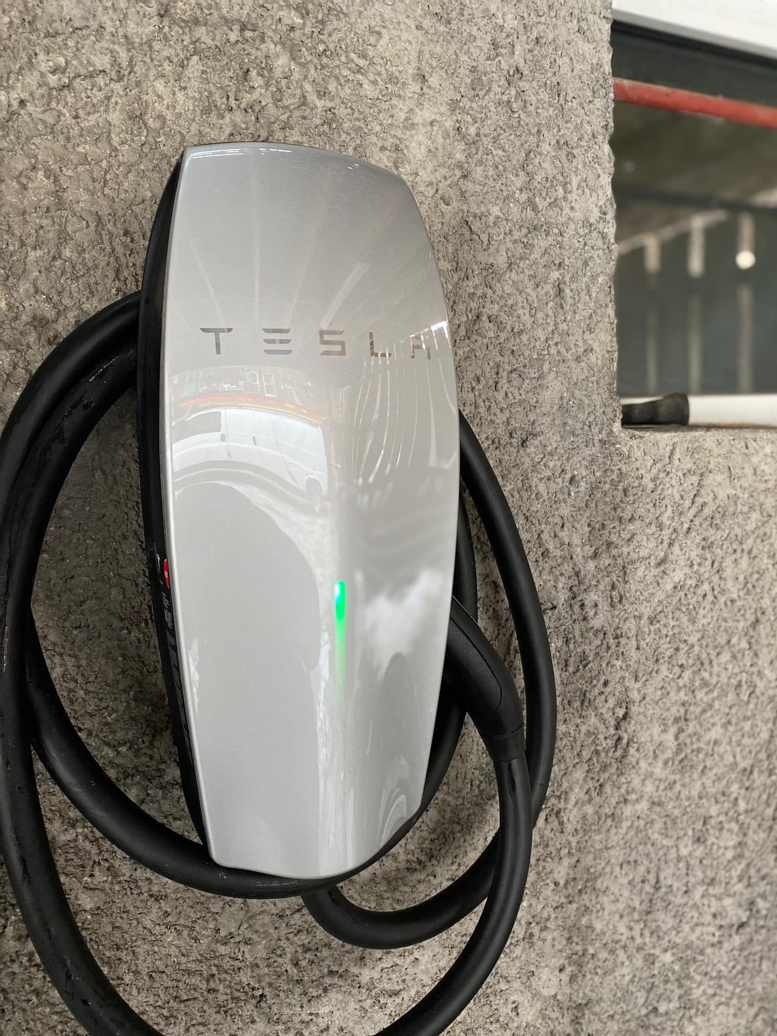 Une borne de recharge Tesla est accrochée à un mur.