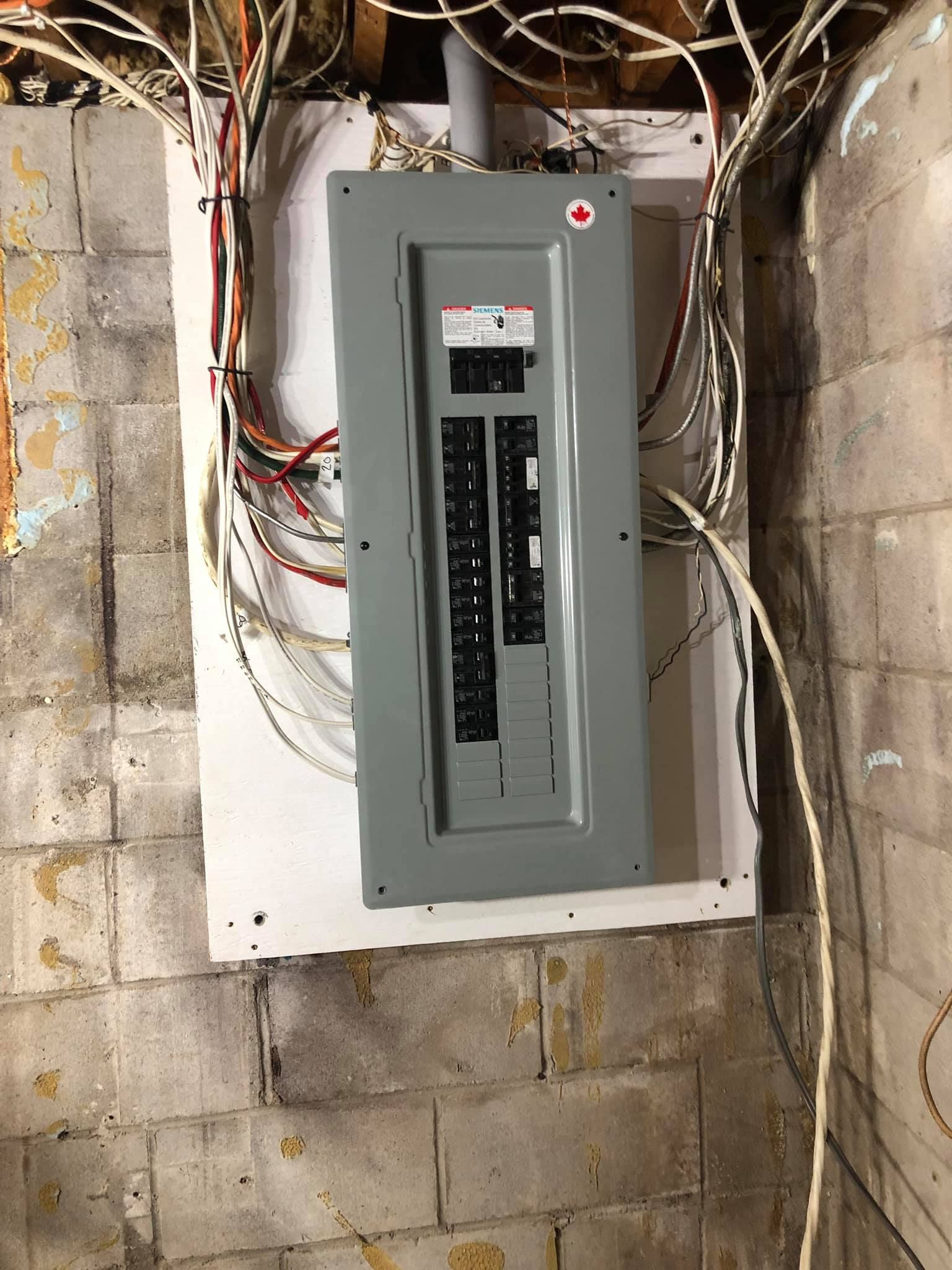 Un boîtier électrique est accroché à un mur de briques.